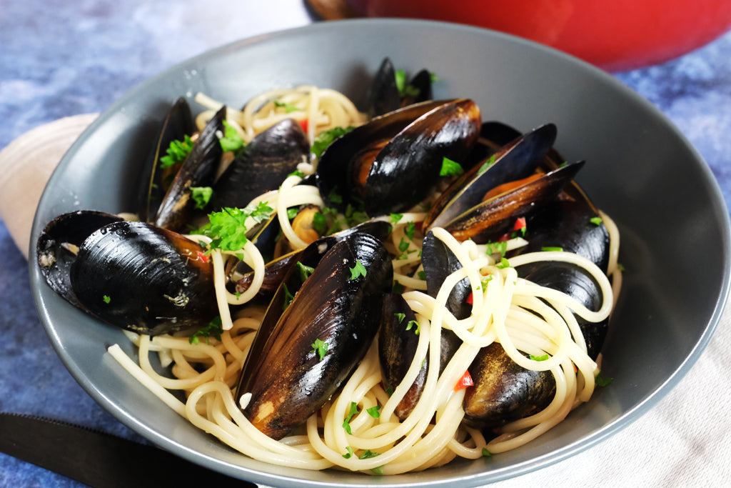 pasta vongole μπροστά από ένα σμαλτωμένο χυτοσίδερο πιάτο balti